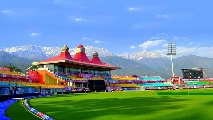 An aerial view of a cricket stadium nestled amidst picturesque mountains.