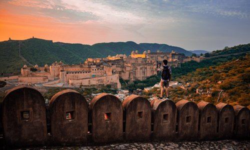 A man standing on a fort wall, gazing into the sunset, captivated by the breathtaking view.