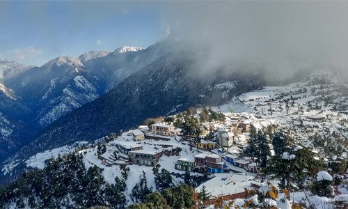 Snowy mountains and houses nestled in a picturesque valley, creating a serene winter landscape.